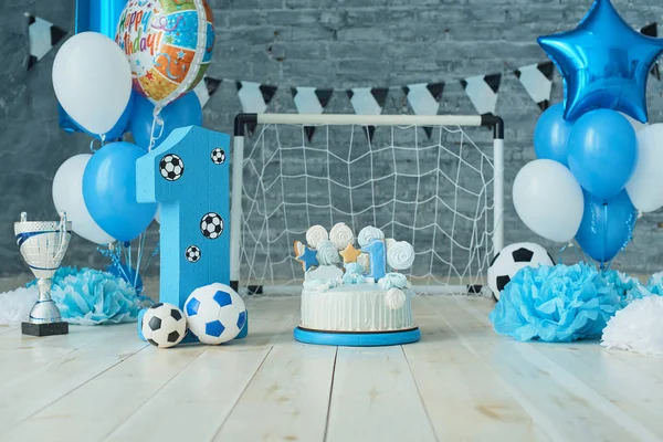 Festive background decoration for birthday with cake, letters saying one and blue balloons in studio, Boy Birthday .Cake Smash first year concept. birthday greetings. Football theme