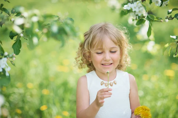小女孩嗅到了蒲公英 女孩嗅花的苹果园 花园与开花的树木 快乐的童年 过敏季节 — 图库照片