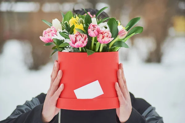 man holding red gift box with beautiful bouquet of blooming flowers, romantic moment, woman day and Valentines Day. delivery courier man delivering box with flowers. Copy space