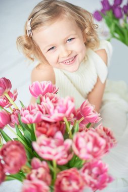 Kız holding Lale elinde. Sevimli gülümseyen küçük kız çiçek Anneler gününde annesi için holding