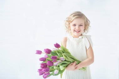 Kız holding Lale elinde. Sevimli gülümseyen küçük kız çiçek Anneler gününde annesi için holding