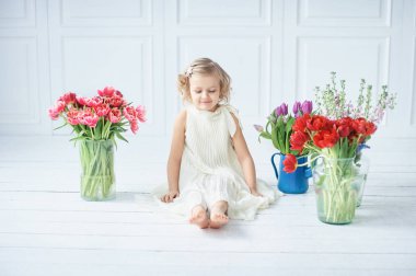 Kız holding Lale elinde. Sevimli gülümseyen küçük kız çiçek Anneler gününde annesi için holding