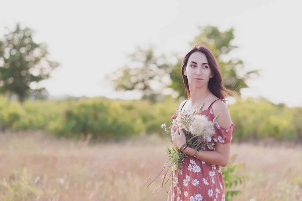 Letní lifestyle portrét krásné romantické dívky držení kytice divokých květů. — Stock fotografie