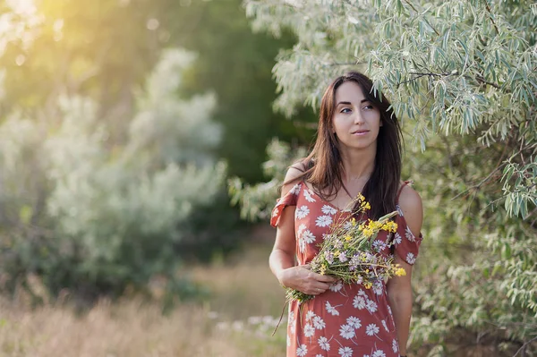 Letní lifestyle portrét krásné romantické dívky držení kytice divokých květů. — Stock fotografie