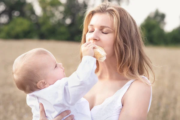 Мати і донька на пшеничному полі. Щаслива сім'я на відкритому повітрі. здорова дитина з матір'ю на пікніку з хлібом і молоком в золотому зерновому полі . — стокове фото