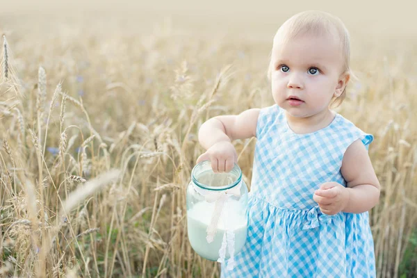 Klein meisje in het tarweveld. gezond kind op de picknick met brood en melk in gouden graanveld. — Stockfoto