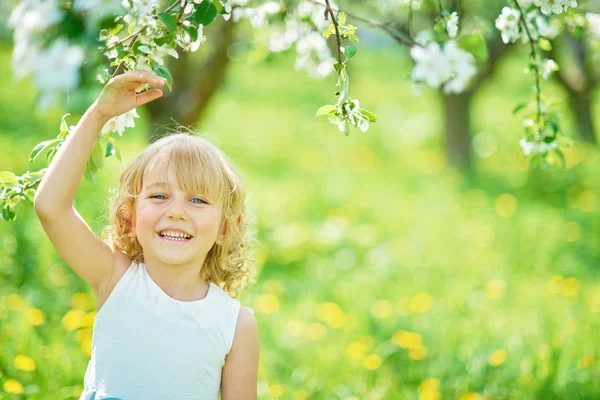 Flicka som sniffar blommor av äppelträdgård. trädgård med blommande träd — Stockfoto
