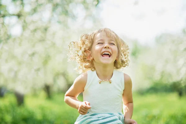 Niña olfateando flores de huerto de manzana. jardín con árboles florecientes — Foto de Stock