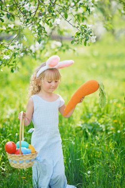 Paskalya yumurtaları ve bahçede tavşan kulakları ile sevimli komik kız. paskalya kavramı. Paskalya yumurtası avında gülen çocuk