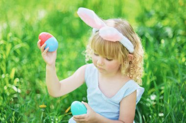 Paskalya yumurtaları ve bahçede tavşan kulakları ile sevimli komik kız. paskalya kavramı. Paskalya yumurtası avında gülen çocuk