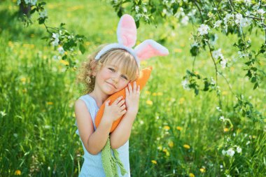 Paskalya yumurtaları ve bahçede tavşan kulakları ile sevimli komik kız. paskalya kavramı. Paskalya yumurtası avında gülen çocuk