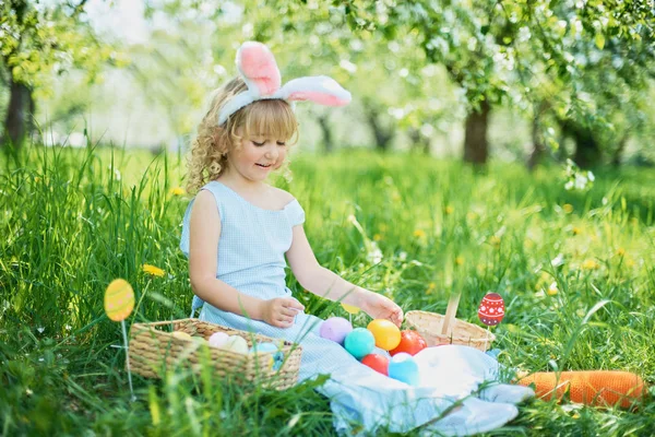 Gadis lucu dengan telur Paskah dan telinga kelinci di taman. konsep easter. Tertawa anak di Paskah berburu telur — Stok Foto