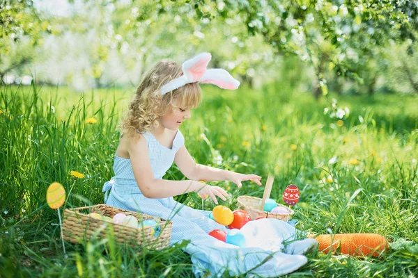Aranyos vicces lány húsvéti tojás és nyuszi füle a kertben. húsvéti koncepcióját. Nevetve gyermek húsvéti tojás vadászat — Stock Fotó
