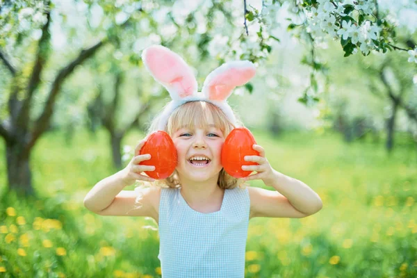 Gadis lucu dengan telur Paskah dan telinga kelinci di taman. konsep easter. Tertawa anak di Paskah berburu telur — Stok Foto