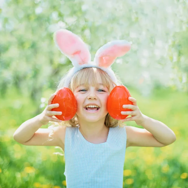 Gadis lucu dengan telur Paskah dan telinga kelinci di taman. konsep easter. Tertawa anak di Paskah berburu telur — Stok Foto