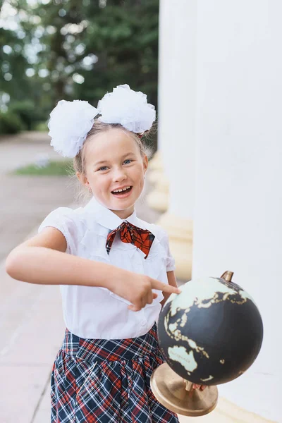 Portrait of beautiful young first-grader Farewell Bell. day of knowledge. beginning of the school year. school equipment. Young girl exploring the globe. — Stock Photo, Image