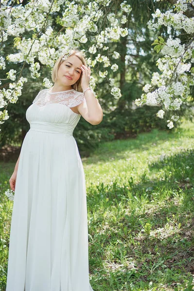 Modo de primavera, bela mulher grávida cheiro árvore de cereja florido, apreciando a natureza, jardim floral branco . — Fotografia de Stock