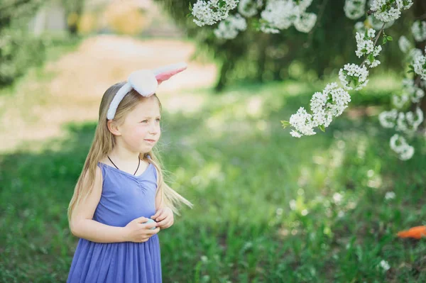 Gadis lucu dengan telur Paskah dan telinga kelinci di taman. konsep easter. Tertawa anak di Paskah berburu telur . — Stok Foto