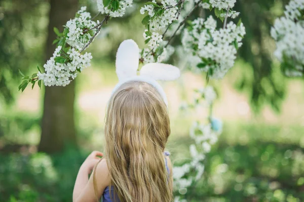 Cute funny girl with Easter eggs and bunny ears at garden. easter concept. Laughing child at Easter egg hunt. — Stock Photo, Image