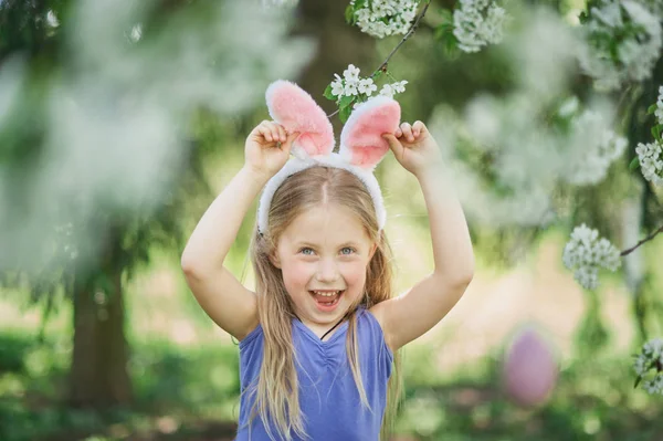 Cute funny girl with Easter eggs and bunny ears at garden. easter concept. Laughing child at Easter egg hunt. — Stock Photo, Image