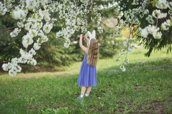 Cute funny girl with Easter eggs and bunny ears at garden. easter concept. Laughing child at Easter egg hunt. — Stock Photo, Image