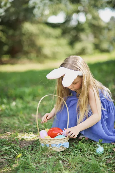 Gadis lucu dengan telur Paskah dan telinga kelinci di taman. konsep easter. Tertawa anak di Paskah berburu telur . — Stok Foto