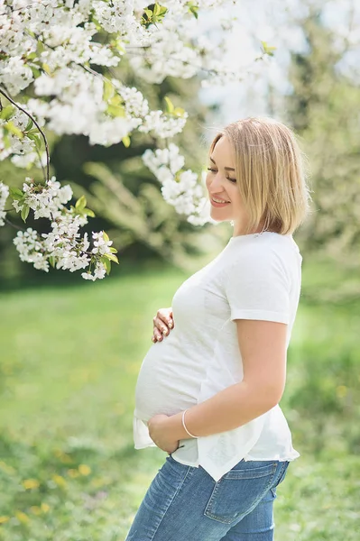 Весняний настрій, красива вагітна жінка пахне квітучим вишневим деревом, насолоджуючись природою, білим квітковим садом . — стокове фото