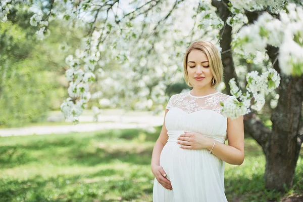 美丽的孕妇放松和享受附近的开花樱桃树在花园里 — 图库照片