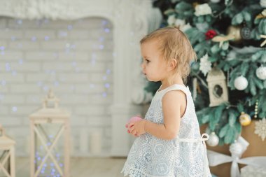 Dekore Noel ağacı yakınında dururken süs eşyası tutan güzel kız 