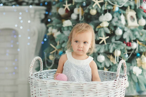 Piękna dziewczyna w pobliżu zdobione choinki z zabawkami drewniany koń biegunach. Szczęśliwego nowego roku. Portret mała dziewczynka — Zdjęcie stockowe