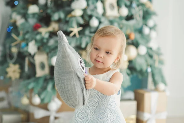 Menina bonita perto da árvore de Natal decorada com brinquedo de madeira cavalo de balanço. Feliz Ano Novo. Retrato menina — Fotografia de Stock