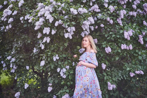 Весеннее настроение, красивая беременная женщина пахнет цветущим деревом, наслаждаясь природой, розовый цветочный сад. будущая мама расслабляется и наслаждается жизнью на природе — стоковое фото