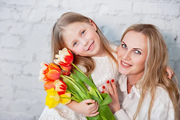 Das Konzept einer glücklichen Familie, Mutterschaft. Mutter mit Tochter mit Blumen. Frauentag — Stockfoto