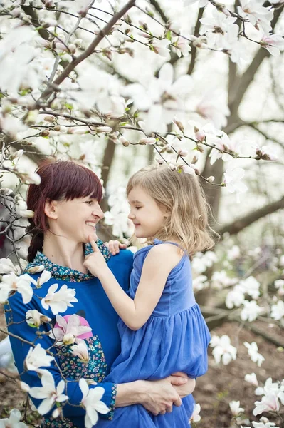 Schöne junge Mutter mit kleinen Mädchen auf dem Arm. das Konzept einer glücklichen Familie, Mutterschaft. Mutter mit ihrer Tochter mit Blumen. — Stockfoto