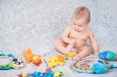 Bebek gelişmekte olan halıya yalan. Mobil olarak oynuyor. eğitici oyuncaklar. Tatlı çocuk kaynıyor ve iskambil ile oyuncaklar üzerinde halı