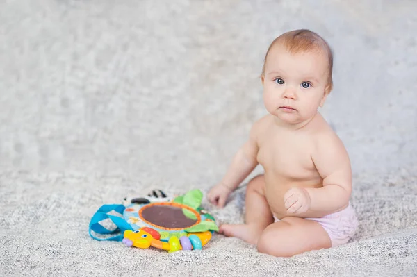 Baby auf einem Teppich liegend. Spielen in mobilen. Lernspielzeug. Süßes Kind krabbelt und spielt mit Spielzeug auf Teppich — Stockfoto