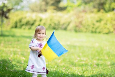 Çocuk, Ukrayna 'nın dalgalanan mavi ve sarı bayrağını tarlada taşıyor. Ukrayna 'nın Bağımsızlık Günü. Bayrak Günü. Anayasa günü. Geleneksel Ukrayna bayrağıyla nakışçı kız.