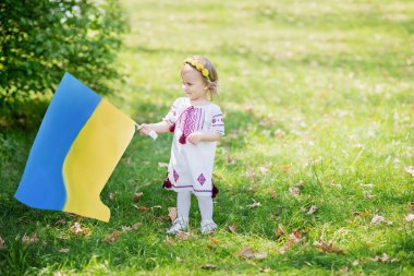 Çocuk, Ukrayna 'nın dalgalanan mavi ve sarı bayrağını tarlada taşıyor. Ukrayna 'nın Bağımsızlık Günü. Bayrak Günü. Anayasa günü. Geleneksel Ukrayna bayrağıyla nakışçı kız.