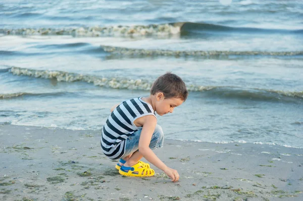 海辺のビーチで石を収集ストライプタンクトップの少年 夏休みの概念 — ストック写真