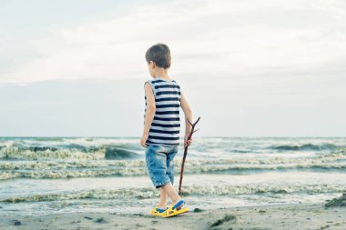 çizgili tank üst ahşap sopa tutan ve sahilde sahilde kum üzerinde çizim çocuk, Yaz tatil konsepti
