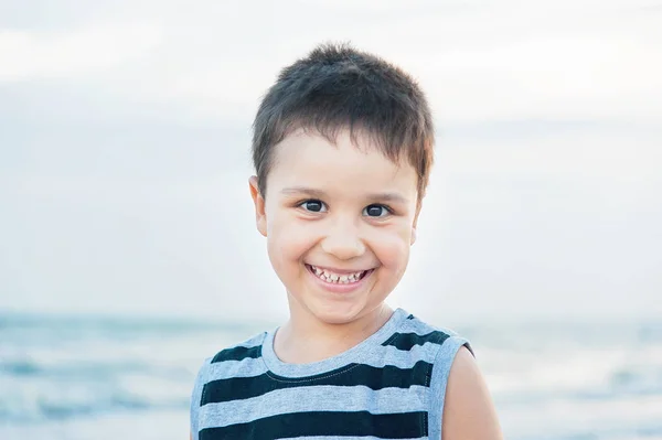 海辺でポーズをとりながらカメラを見るタンクトップで魅力的なハンサムな笑顔の少年の肖像 — ストック写真