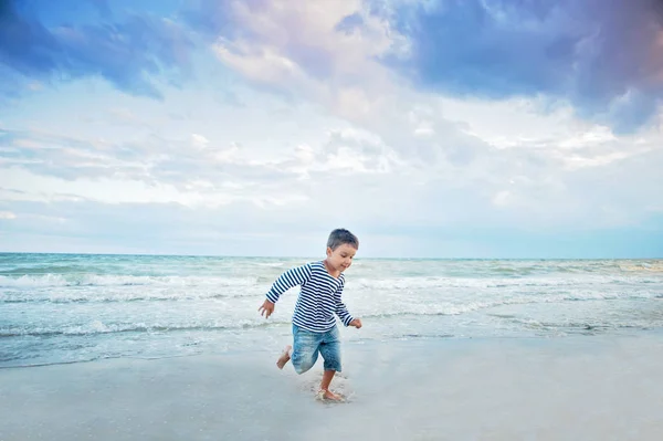 海辺のビーチで走るストライプタンクトップの少年 夏休みのコンセプト — ストック写真