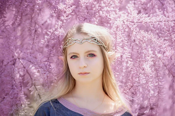 Peri masalı kızı. Gizemli elf kızı portresi. Cosplay karakteri. Çiçek açan bir bahçede elf portresi. Uzun kulaklı bir kız dokunur. — Stok fotoğraf