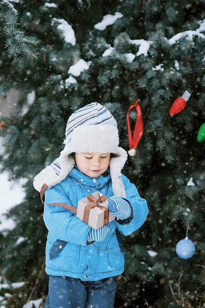 Μητέρα και γιος διακοσμούν το χριστουγεννιάτικο δέντρο υπαίθρια σε ένα χειμερινό πάρκο. Δώρα και χριστουγεννιάτικα δέντρα. — Φωτογραφία Αρχείου