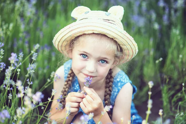 夏の紫色のラベンダー畑で花を嗅ぐ微笑み小さな女の子 — ストック写真