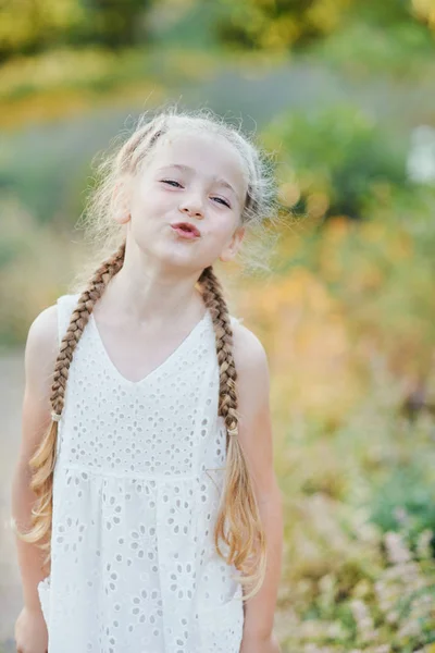 재미 소녀 들고 머리 plaits. 작은 귀여운 소녀 와 긴 금발 머리 야외. 감정을 표현하는 아이. 만우절. — 스톡 사진