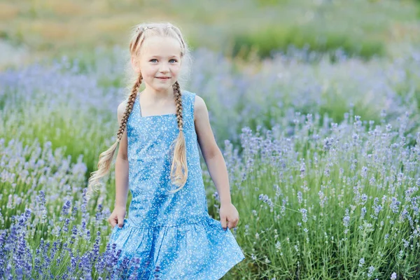 Niña en el campo de lavanda. Fantasía infantil. Chica sonriente oliendo flores en el campo de lavanda púrpura de verano . —  Fotos de Stock