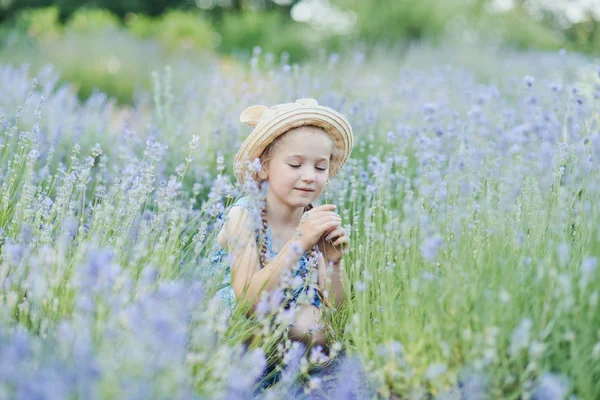 Kleines Mädchen im Lavendelfeld. Kinderfantasie. Lächeln Mädchen schnüffelt Blumen im Sommer lila Lavendelfeld. — Stockfoto