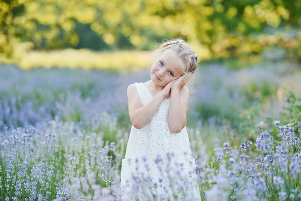 Kis lány levendula területén. gyerekek fantáziáját. Mosolygós lány szippantás virágok nyáron lila levendula mező. — Stock Fotó