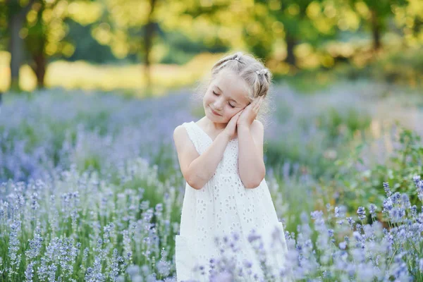 Niña en el campo de lavanda. Fantasía infantil. Chica sonriente oliendo flores en el campo de lavanda púrpura de verano . — Foto de Stock